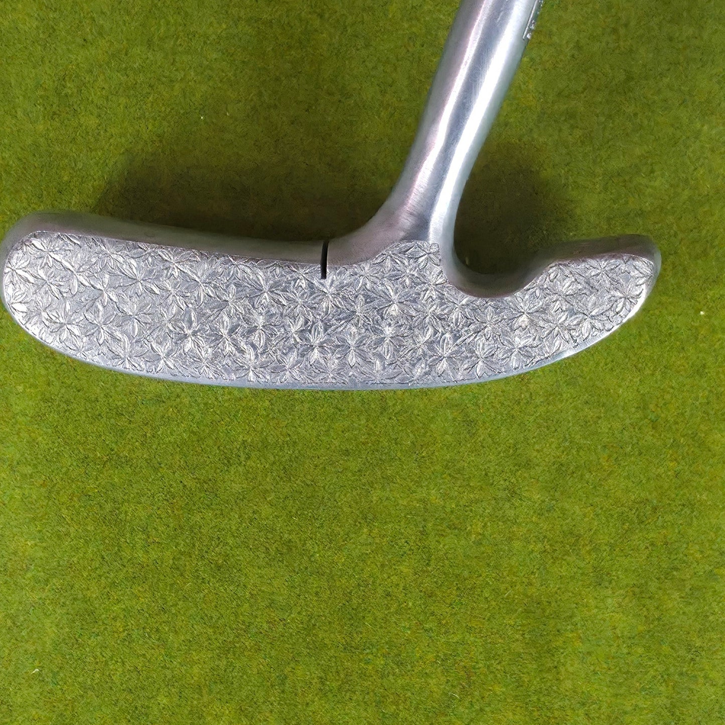 Metal tool with textured handle held by a hand on a green background