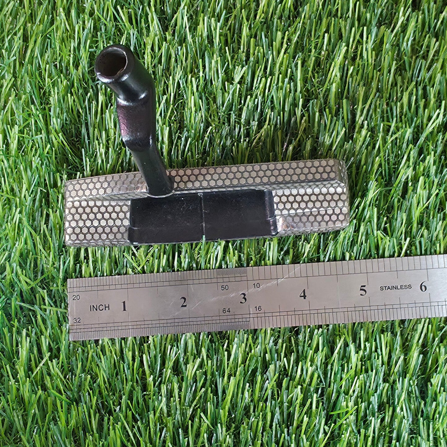 Golf club head, golf ball, and ruler on artificial grass