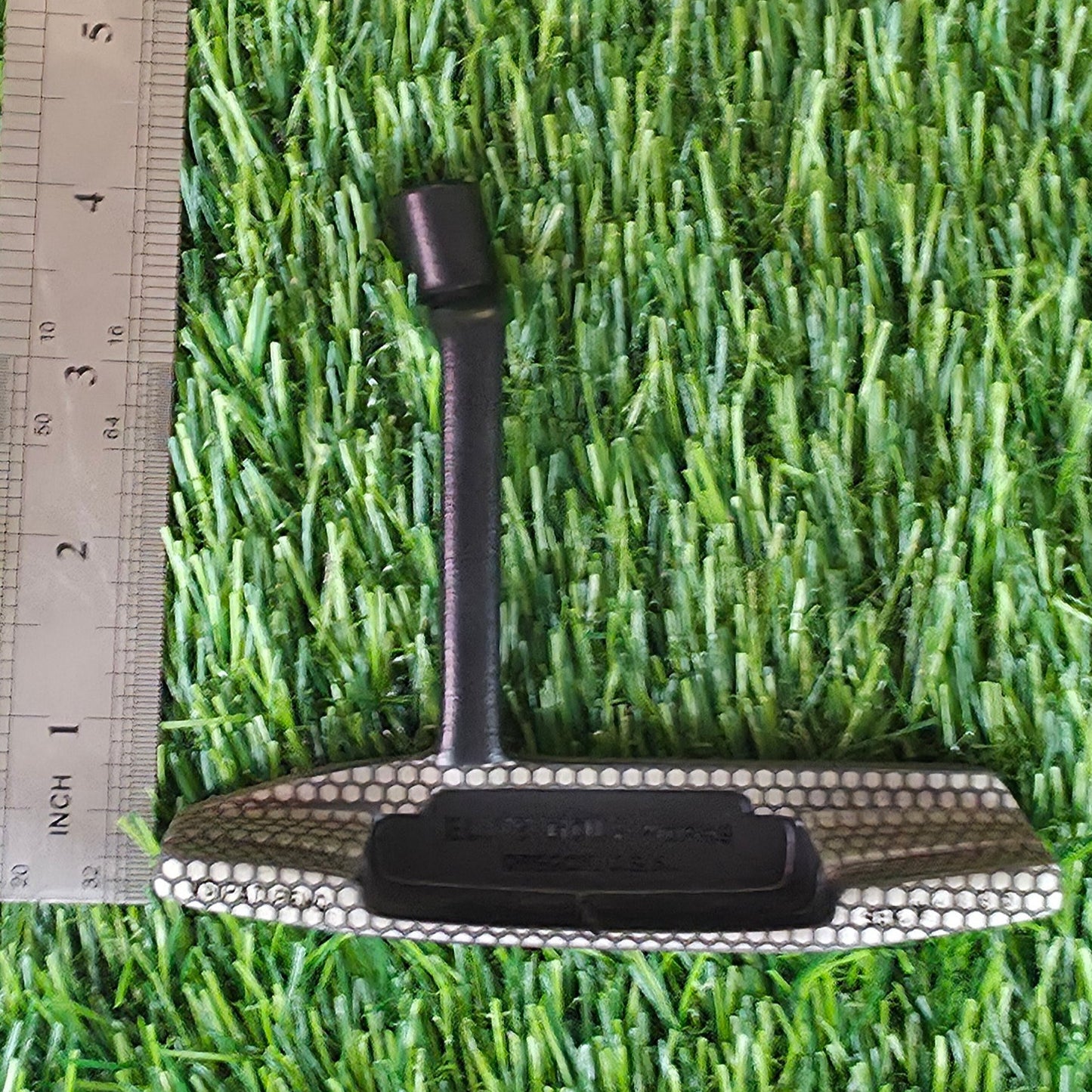 Green artificial grass with a ruler for scale on a green surface