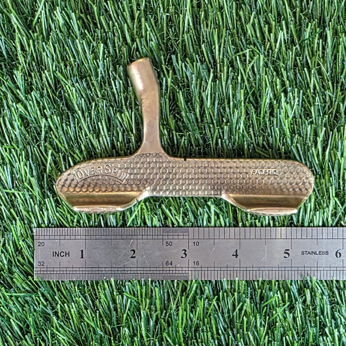Gold broom and ruler on artificial grass with wooden floor border