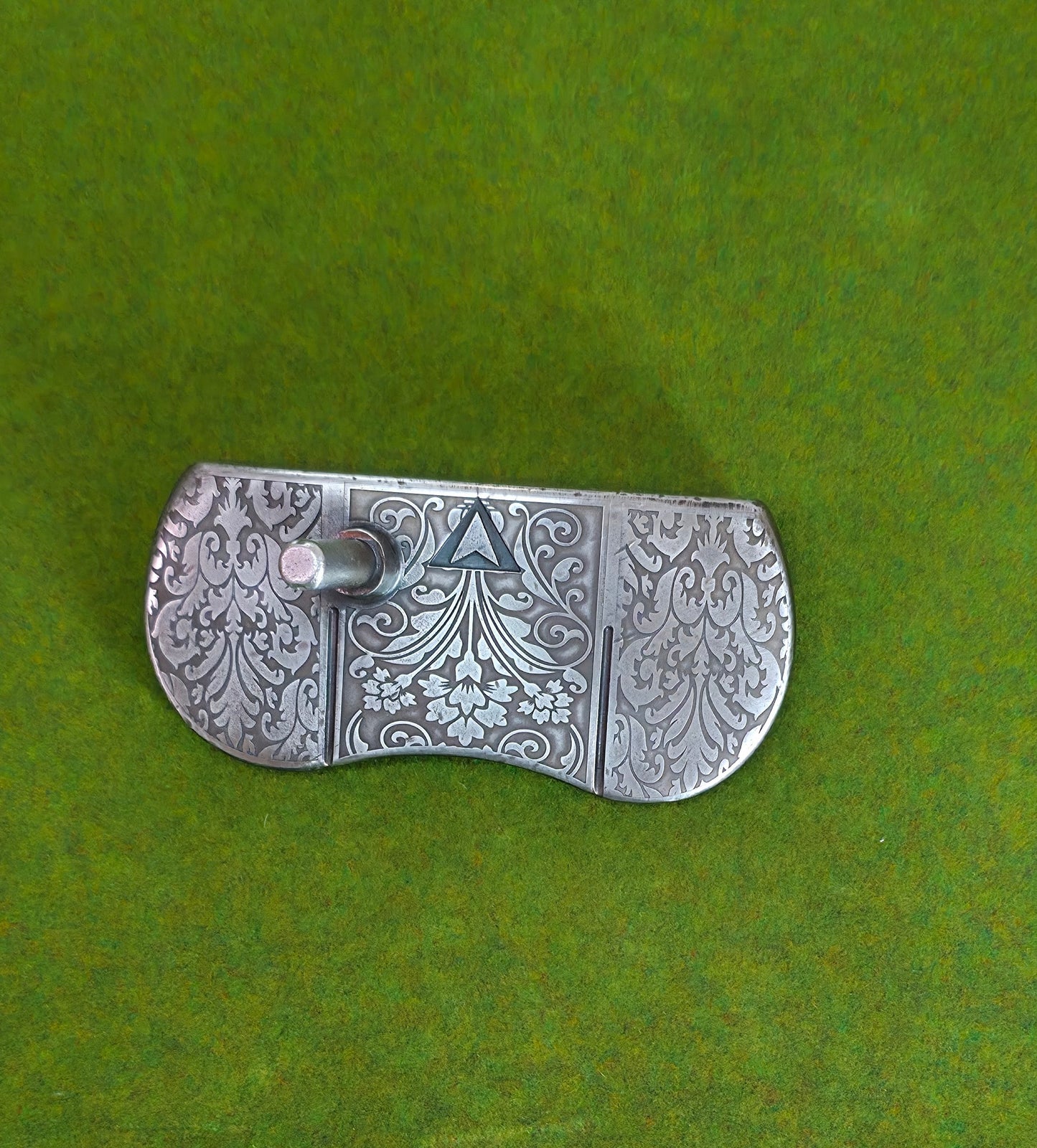 Custom engraved golf putter head with ornate floral and scrollwork design in antique brushed metal finish. Features deep engraving for durability, luxury artisan detailing, and an elegant symmetrical pattern. Perfect for golfers seeking a unique club, golf collectors, or as a personalized gift with initials, logos, or dates added. A blend of performance and craftsmanship designed to stand out on the green or in a golf display collection.