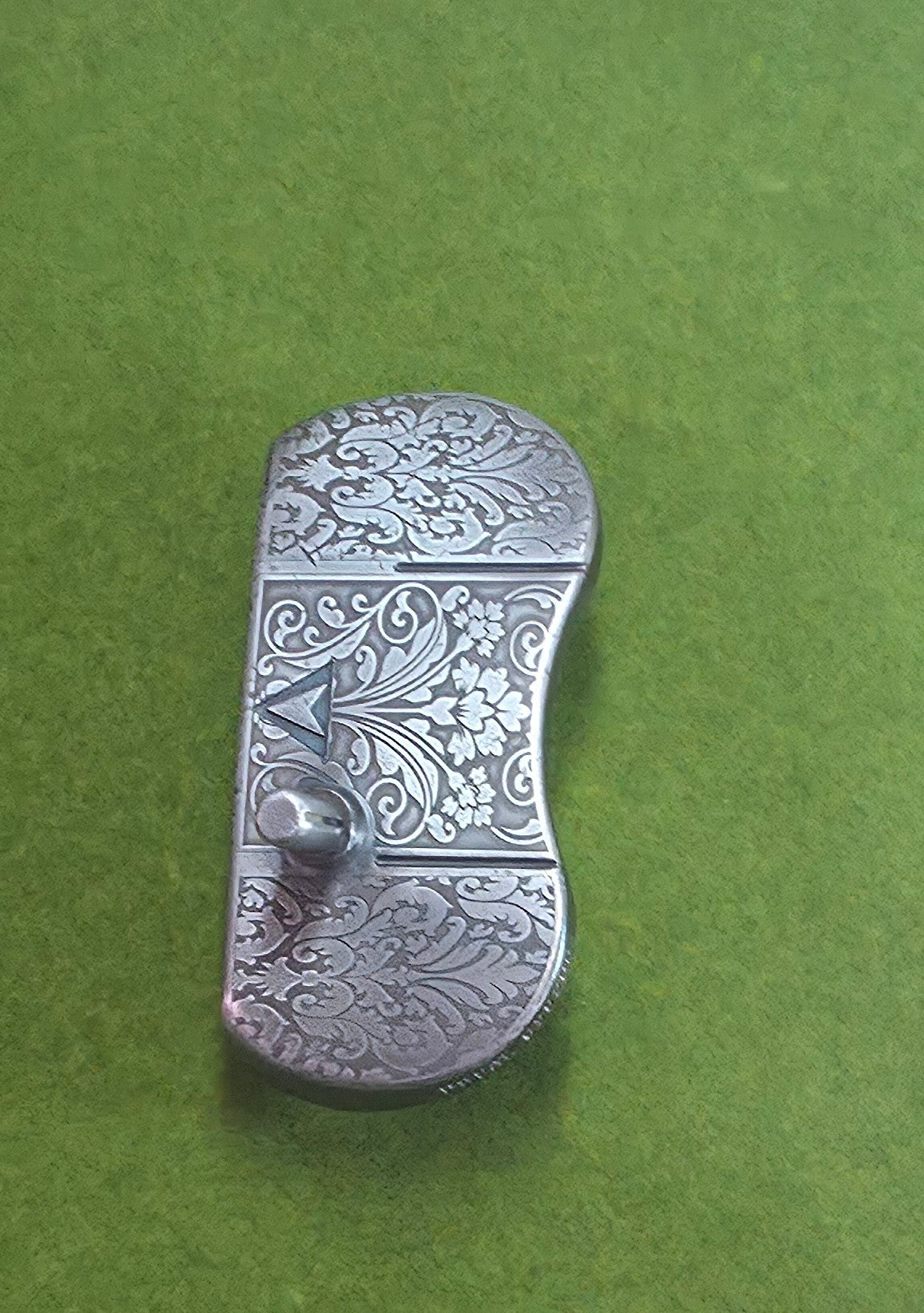 Custom engraved golf putter head with ornate floral and scrollwork design in antique brushed metal finish. Features deep engraving for durability, luxury artisan detailing, and an elegant symmetrical pattern. Perfect for golfers seeking a unique club, golf collectors, or as a personalized gift with initials, logos, or dates added. A blend of performance and craftsmanship designed to stand out on the green or in a golf display collection.