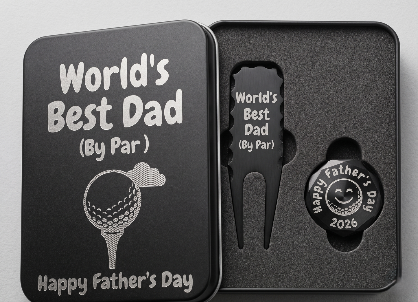 Black metal golf gift set for Father's Day in a custom engraved tin box. Inside sits a customized divot repair tool and a round ball marker resting in foam. Engraving options include sentimental quotes from kids, funny dad golf stats like three-putts, topographic patterns with initials, or classic crossed golf clubs. A perfect personalized fathers or grandpa gift for the golf course. The dark matte metal provides high contrast for the silver laser engraving, making the text pop nicely.