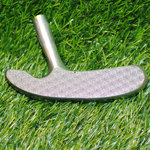 Golf putter head on a grassy background
