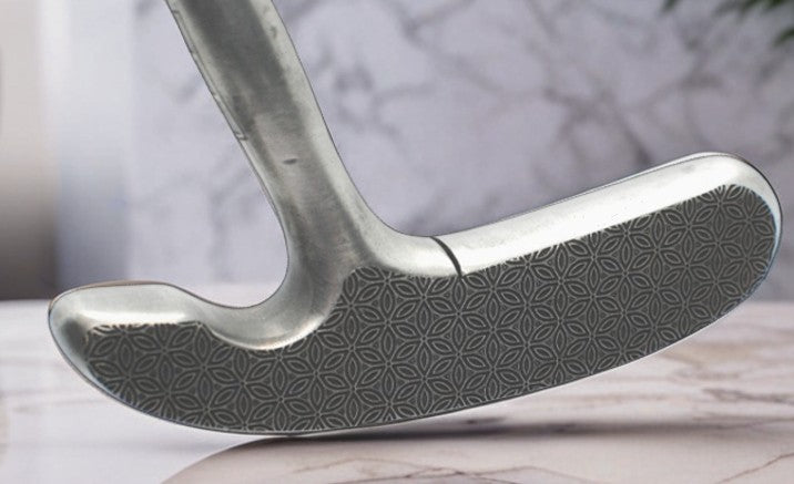 Close-up of a golf club head with a detailed pattern on a neutral background