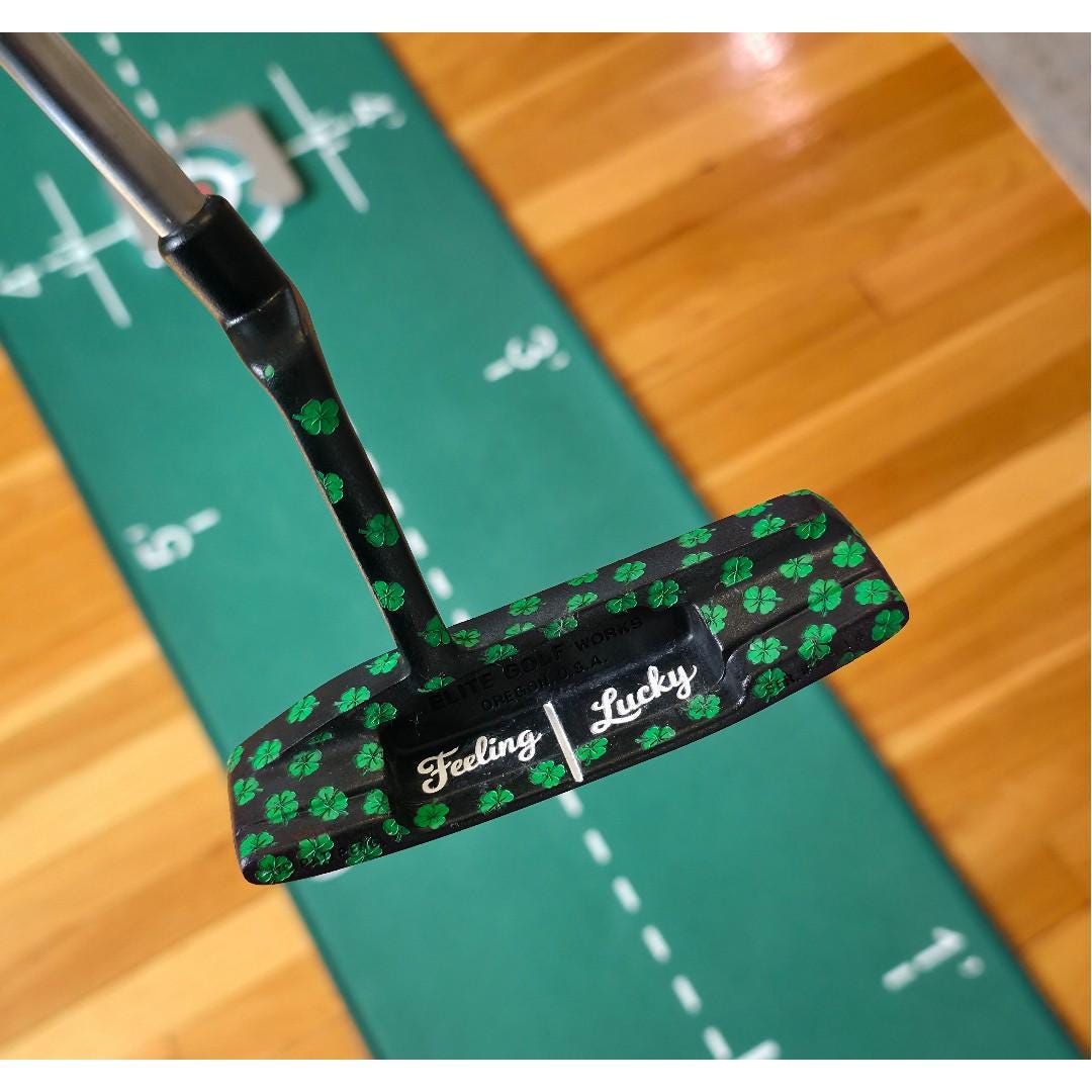 Custom black golf putter with green shamrock clover pattern, "Feeling Lucky" engraving, white alignment line, and Elite Golf Works USA branding — novelty St. Patrick’s Day golf gift for Irish golf lovers and collectors  custom golf putter  black putter head  green shamrock / clover pattern  “Feeling Lucky” engraving  alignment line  Elite Golf Works USA  St. Patrick’s Day golf gift  novelty golf club  Irish golf lovers  collectors