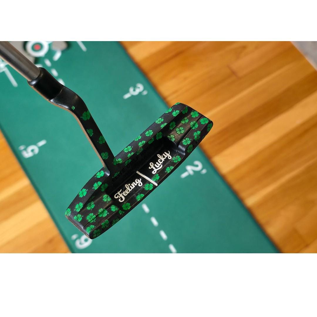 Custom black golf putter with green shamrock clover pattern, "Feeling Lucky" engraving, white alignment line, and Elite Golf Works USA branding — novelty St. Patrick’s Day golf gift for Irish golf lovers and collectors  custom golf putter  black putter head  green shamrock / clover pattern  “Feeling Lucky” engraving  alignment line  Elite Golf Works USA  St. Patrick’s Day golf gift  novelty golf club  Irish golf lovers  collectors