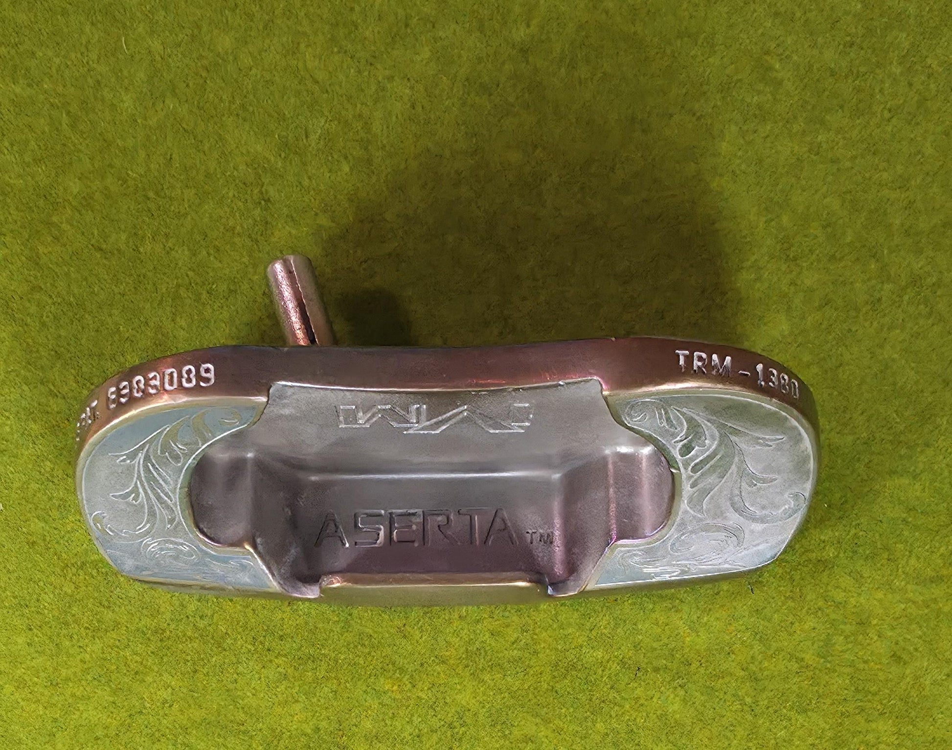 Custom engraved golf putter head with ornate floral and scrollwork design in antique brushed metal finish. Features deep engraving for durability, luxury artisan detailing, and an elegant symmetrical pattern. Perfect for golfers seeking a unique club, golf collectors, or as a personalized gift with initials, logos, or dates added. A blend of performance and craftsmanship designed to stand out on the green or in a golf display collection