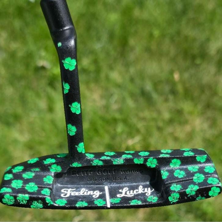 Custom black golf putter with green shamrock clover pattern, "Feeling Lucky" engraving, white alignment line, and Elite Golf Works USA branding — novelty St. Patrick’s Day golf gift for Irish golf lovers and collectors  custom golf putter  black putter head  green shamrock / clover pattern  “Feeling Lucky” engraving  alignment line  Elite Golf Works USA  St. Patrick’s Day golf gift  novelty golf club  Irish golf lovers  collectors