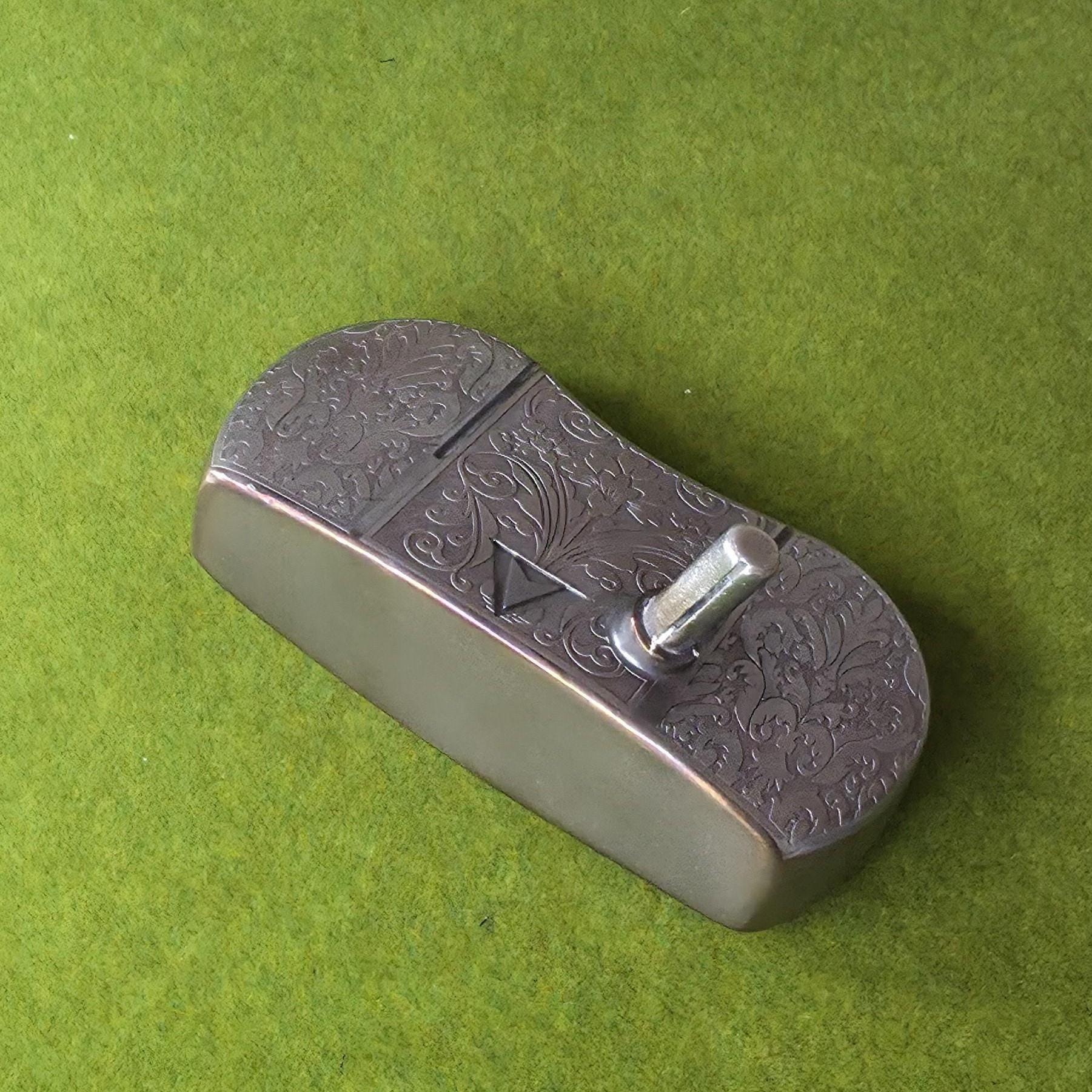 Custom engraved golf putter head with ornate floral and scrollwork design in antique brushed metal finish. Features deep engraving for durability, luxury artisan detailing, and an elegant symmetrical pattern. Perfect for golfers seeking a unique club, golf collectors, or as a personalized gift with initials, logos, or dates added. A blend of performance and craftsmanship designed to stand out on the green or in a golf display collection
