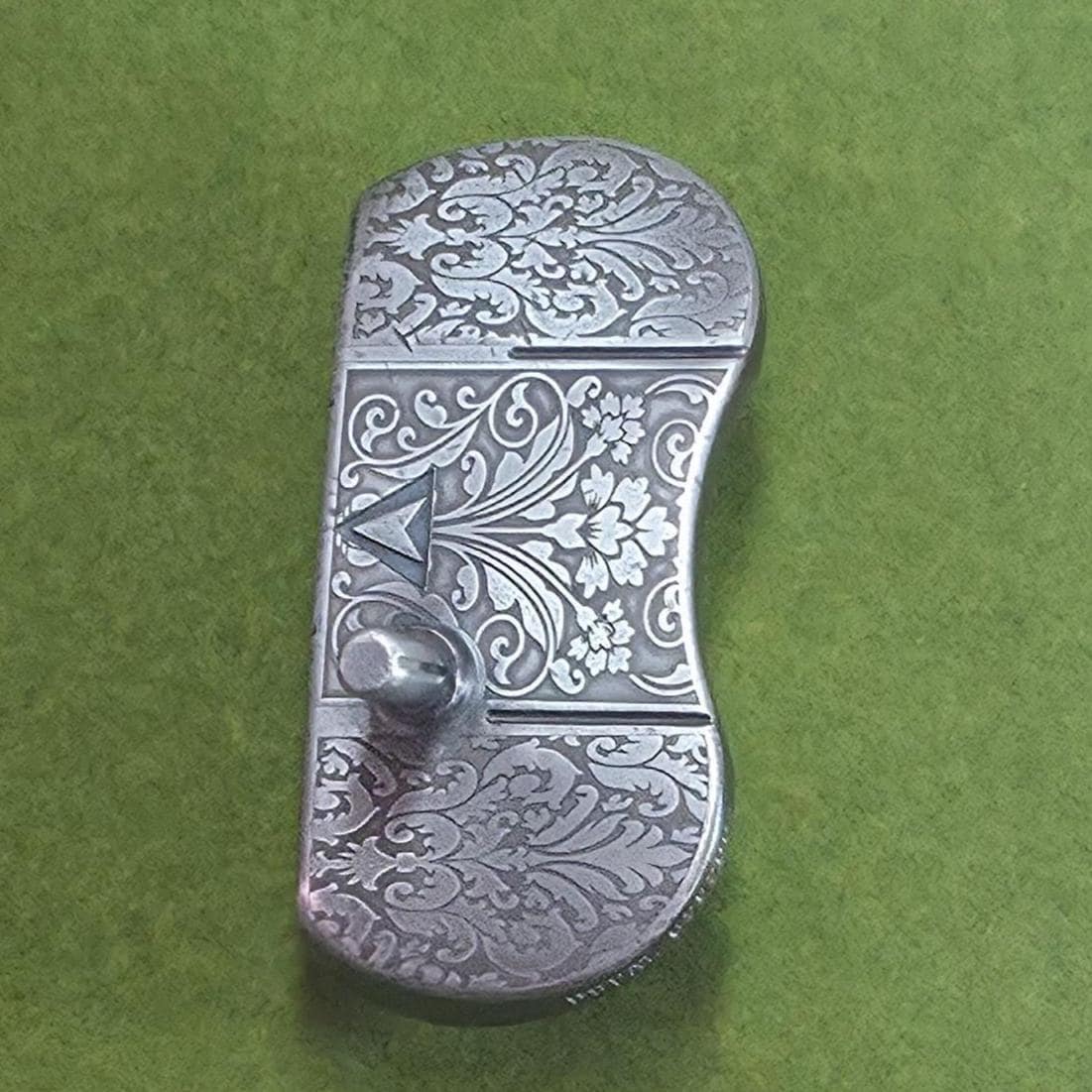 Custom engraved golf putter head with ornate floral and scrollwork design in antique brushed metal finish. Features deep engraving for durability, luxury artisan detailing, and an elegant symmetrical pattern. Perfect for golfers seeking a unique club, golf collectors, or as a personalized gift with initials, logos, or dates added. A blend of performance and craftsmanship designed to stand out on the green or in a golf display collection
