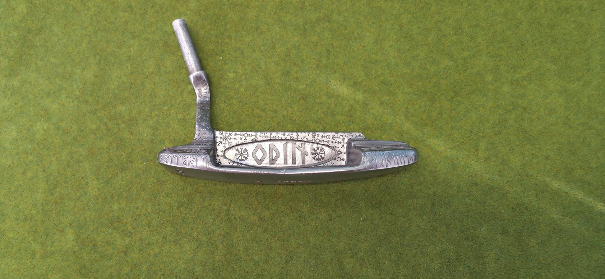 Custom hand-engraved Odin themed golf putter with Norse runes, Viking symbols, and raven designs. Features darkened engravings, raw steel finish, and detailed artwork on the face, back cavity, sole, and neck. Inspired by Norse mythology and Viking craftsmanship. Perfect for golf collectors or players who want a unique personalized putter.