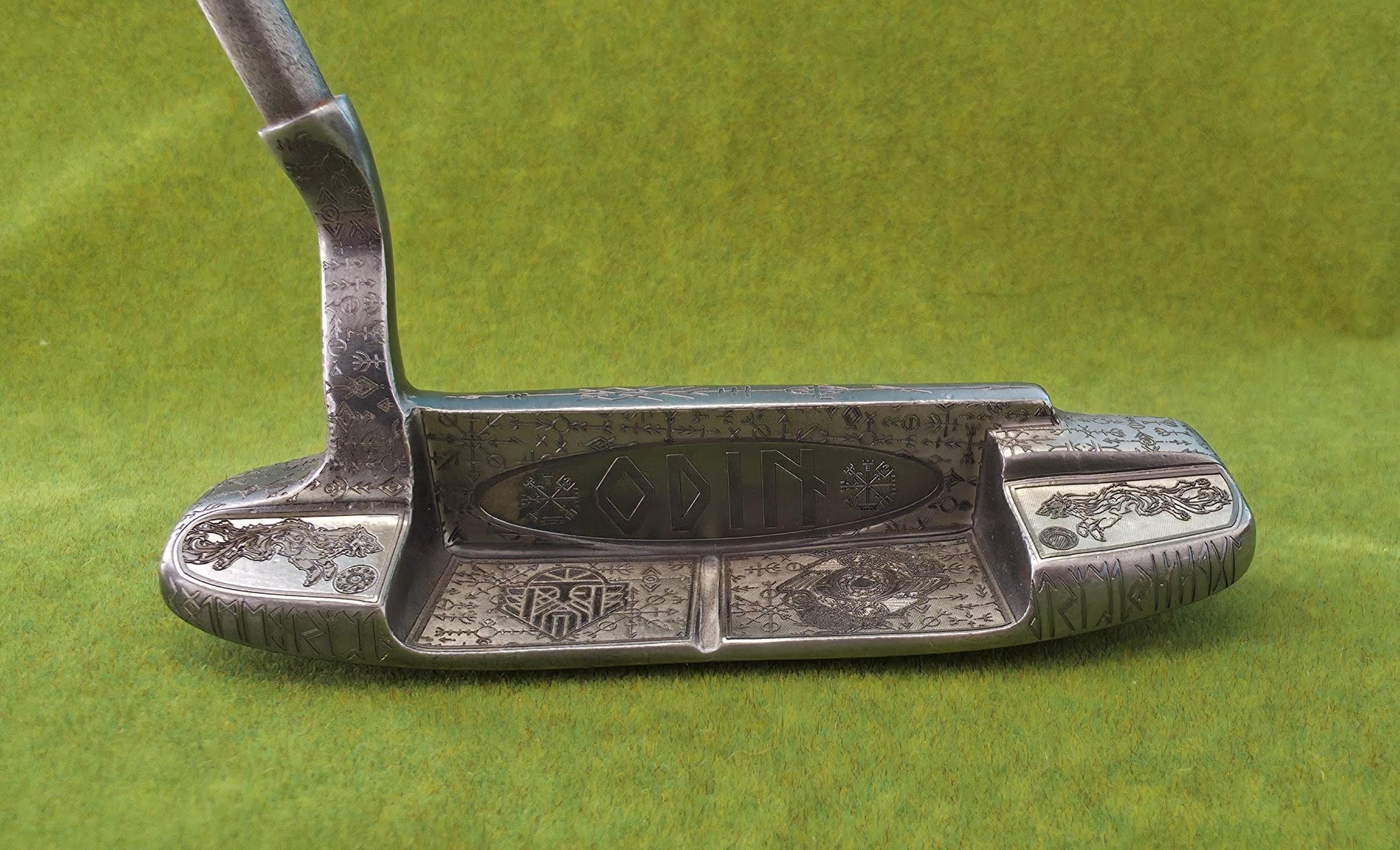 Custom hand-engraved Odin themed golf putter with Norse runes, Viking symbols, and raven designs. Features darkened engravings, raw steel finish, and detailed artwork on the face, back cavity, sole, and neck. Inspired by Norse mythology and Viking craftsmanship. Perfect for golf collectors or players who want a unique personalized putter.