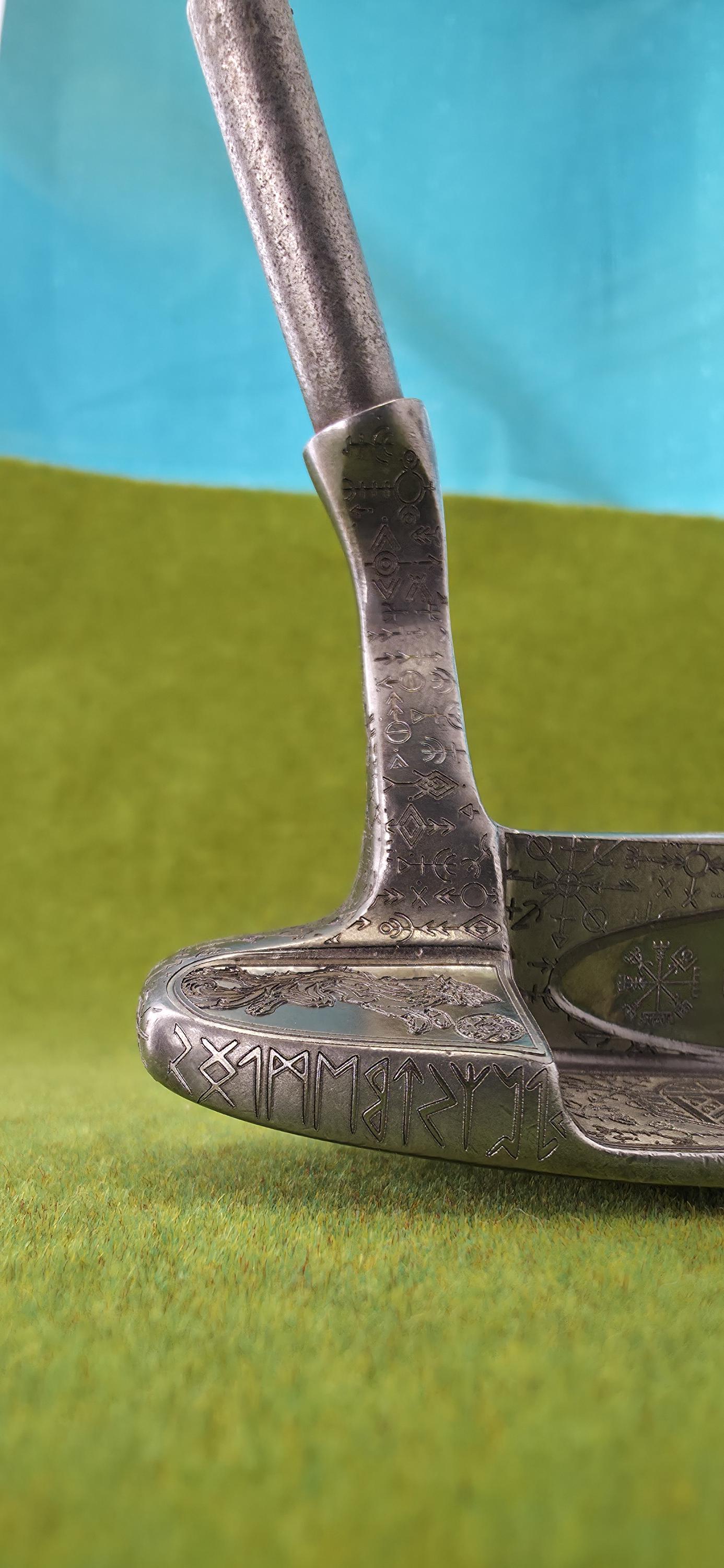 Custom hand-engraved Odin themed golf putter with Norse runes, Viking symbols, and raven designs. Features darkened engravings, raw steel finish, and detailed artwork on the face, back cavity, sole, and neck. Inspired by Norse mythology and Viking craftsmanship. Perfect for golf collectors or players who want a unique personalized putter.