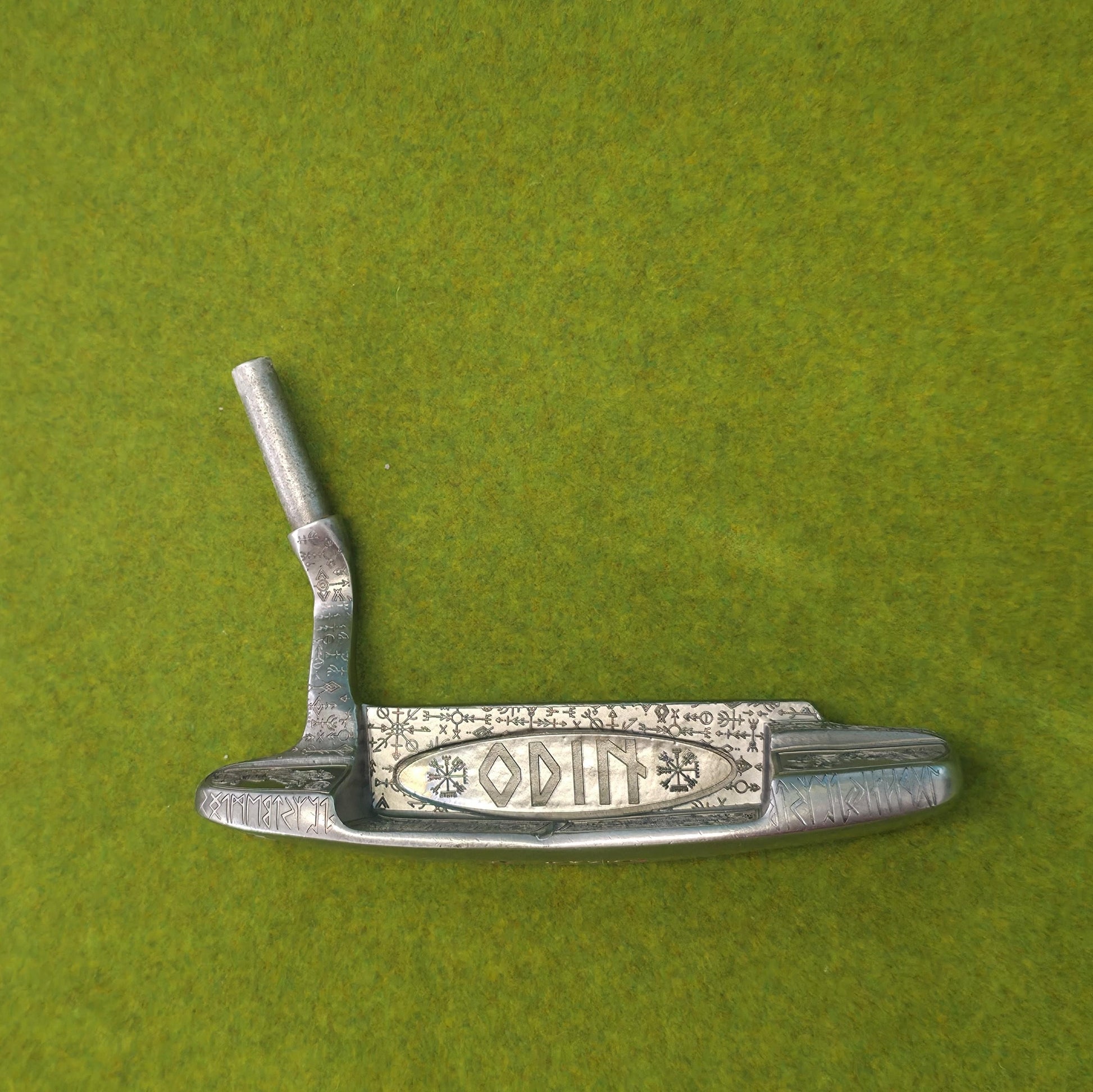 Custom hand-engraved Odin themed golf putter with Norse runes, Viking symbols, and raven designs. Features darkened engravings, raw steel finish, and detailed artwork on the face, back cavity, sole, and neck. Inspired by Norse mythology and Viking craftsmanship. Perfect for golf collectors or players who want a unique personalized putter.