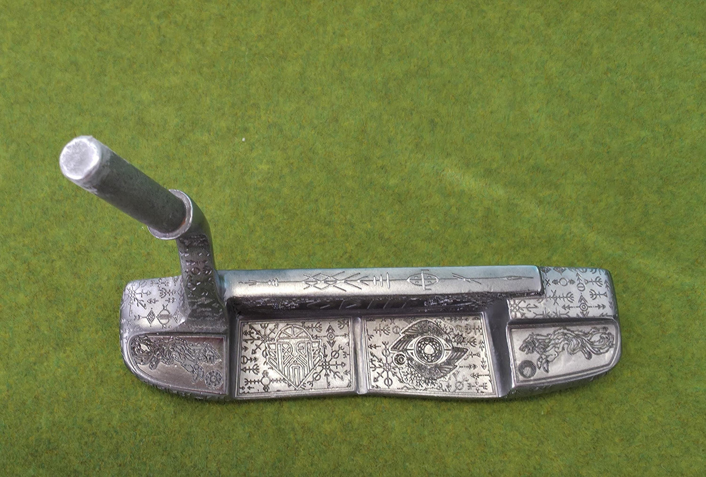 Custom hand-engraved Odin themed golf putter with Norse runes, Viking symbols, and raven designs. Features darkened engravings, raw steel finish, and detailed artwork on the face, back cavity, sole, and neck. Inspired by Norse mythology and Viking craftsmanship. Perfect for golf collectors or players who want a unique personalized putter.