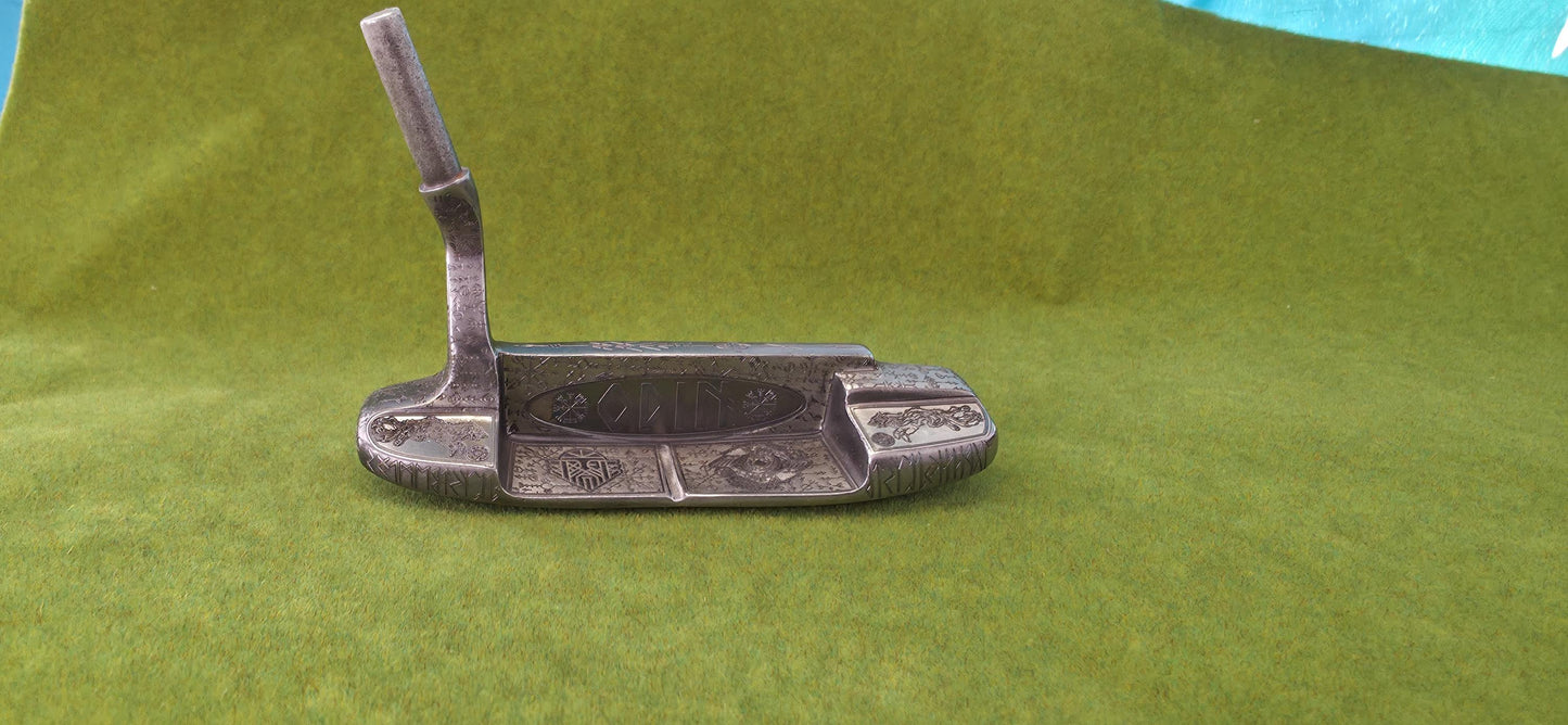 Custom hand-engraved Odin themed golf putter with Norse runes, Viking symbols, and raven designs. Features darkened engravings, raw steel finish, and detailed artwork on the face, back cavity, sole, and neck. Inspired by Norse mythology and Viking craftsmanship. Perfect for golf collectors or players who want a unique personalized putter.
