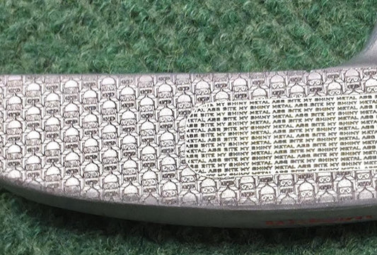 Detailed view of a custom laser engraved Wilson putter head with Space theme. Features Space Crew on the back flange with the Planet Express ship. The face is precision-engraved with "Bite My Shiny Metal" pattern. Hand-painted red and green accents on a satin steel finish. Perfect unique golf gift for anime fans, collectors