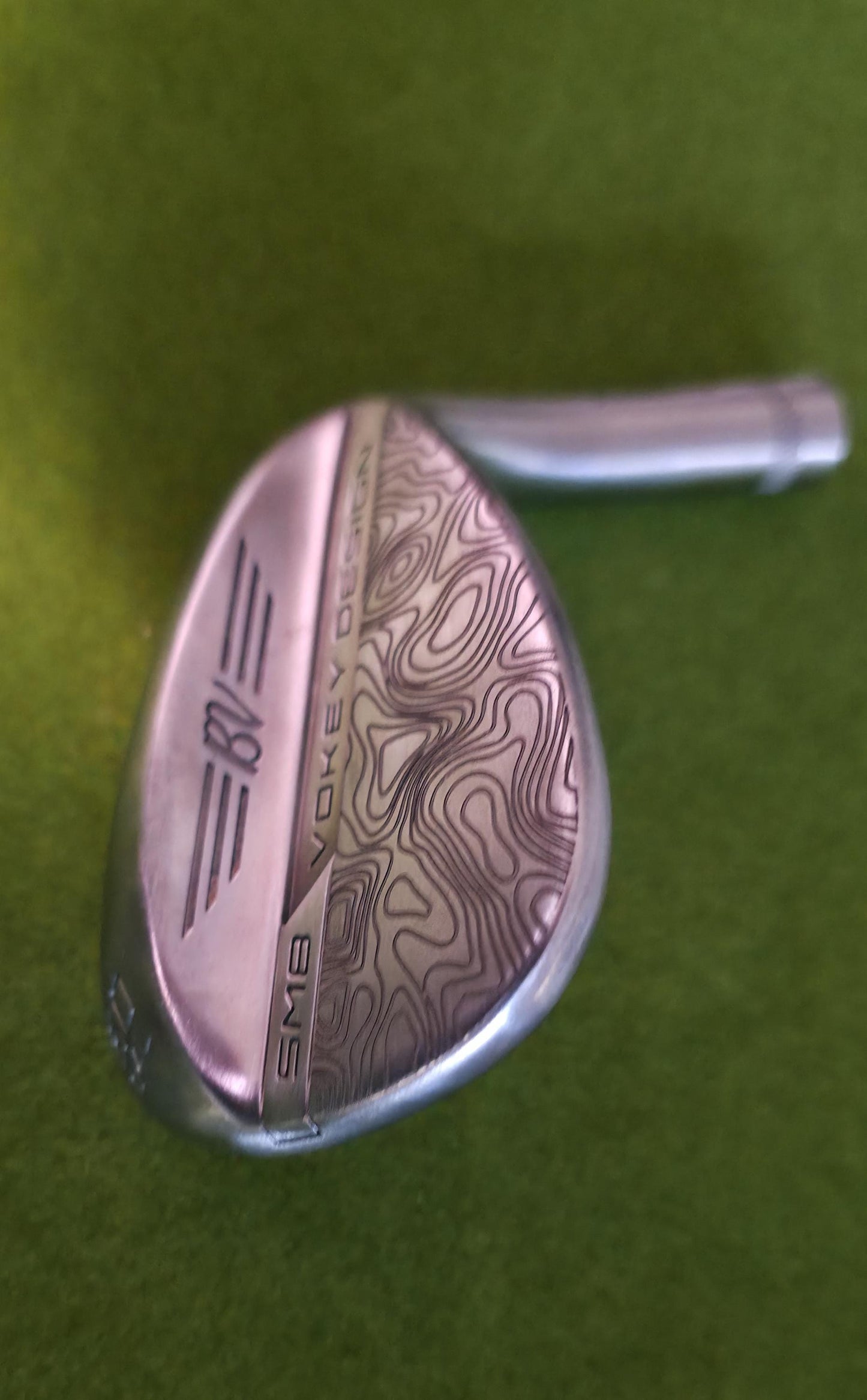 Custom laser-engraved Titleist Vokey SM8 golf wedge by Par Bros Golf, featuring a detailed, wrap-around topographic map pattern. The intricate artisan etching covers the steel clubhead, highlighting unique personalized craftsmanship. Titleist Vokey Design SM8 wedge with deep, intricate topographic map-style laser engraving covering the clubhead's surface. The 'BV' logo, 'SM8', and 'VOKEY DESIGN' markings are clearly visible on the brushed steel finish.