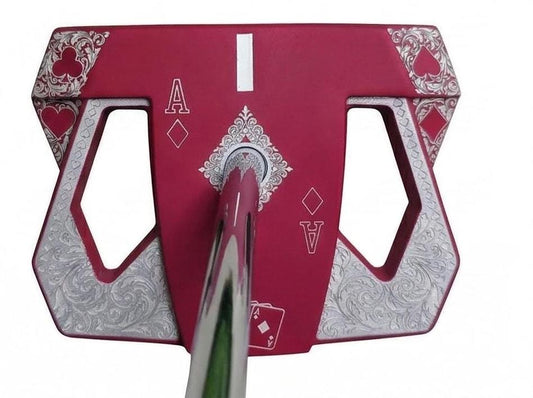 Detailed front view of a custom milled, deep matte red mallet putter head. Intricate playing card suit (Hearts, Diamonds, Spades, Clubs) engravings in satin silver. Features a fanned card graphic, "Ace of Diamonds" symbols, central hole, and center alignment aid. Engraved hearts on corners. ngled top-down view of a custom red mallet putter head resting on green artificial turf, showing the detailed silver scrollwork wings with small suit symbols.