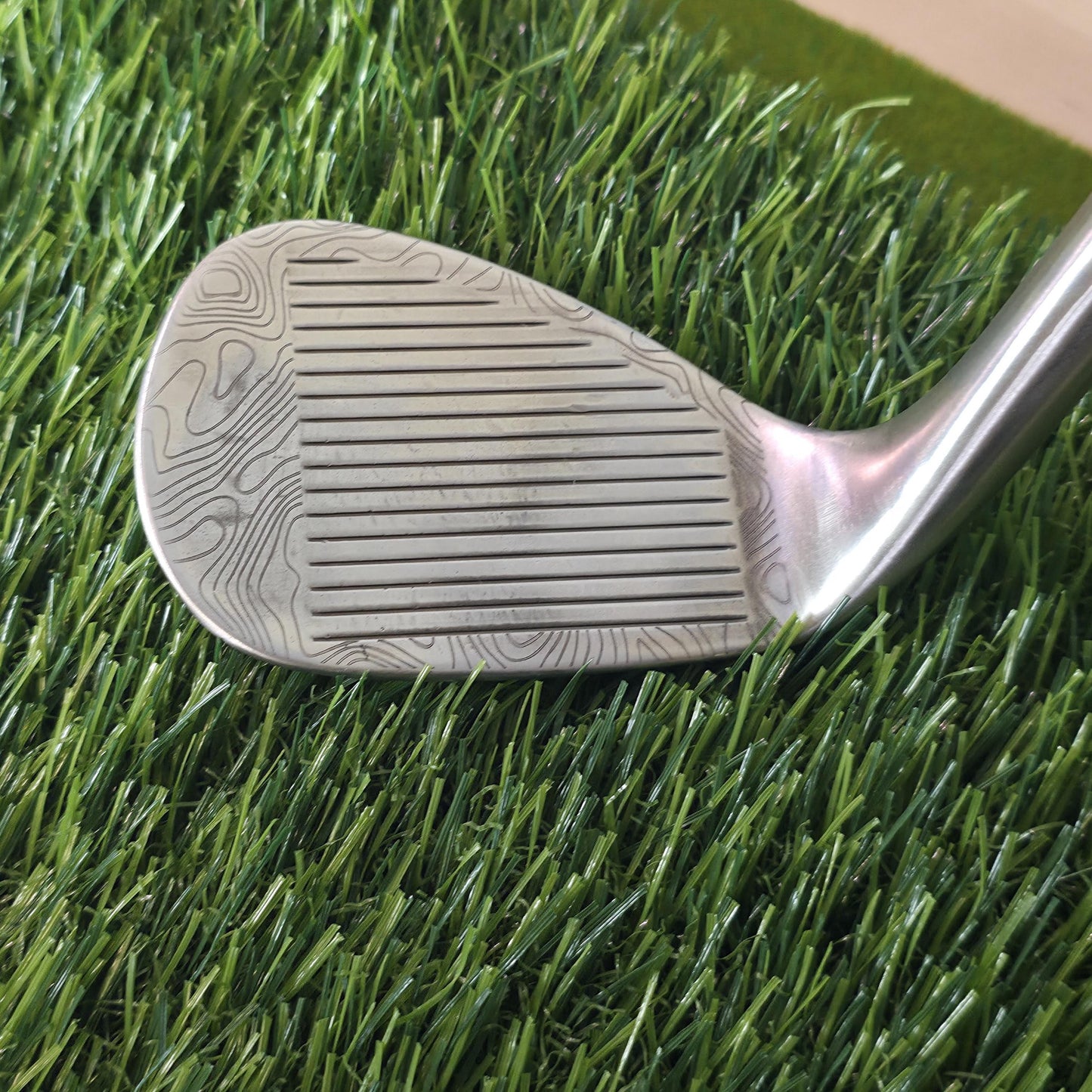 Custom laser-engraved Titleist Vokey SM8 golf wedge by Par Bros Golf, featuring a detailed, wrap-around topographic map pattern. The intricate artisan etching covers the steel clubhead, highlighting unique personalized craftsmanship. Titleist Vokey Design SM8 wedge with deep, intricate topographic map-style laser engraving covering the clubhead's surface. The 'BV' logo, 'SM8', and 'VOKEY DESIGN' markings are clearly visible on the brushed steel finish.
